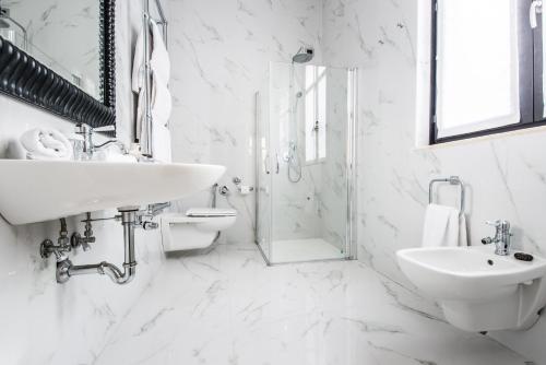 biała łazienka z umywalką i prysznicem w obiekcie Vmaison Hotel Messina w mieście Mesyna