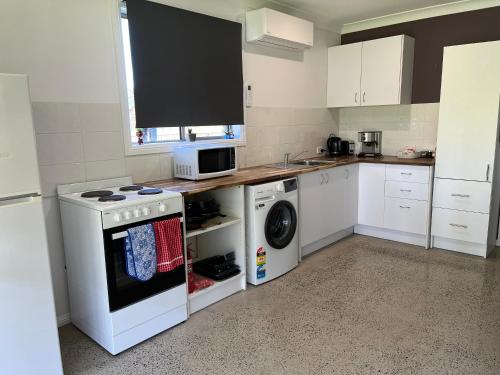 a kitchen with a stove and a washer and dryer at Bimbimbie retreat in Jeremadra