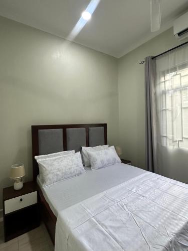 a bedroom with a bed with white sheets and a window at Blue wave loft master bedroom in Dar es Salaam