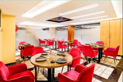 a dining room with red chairs and tables at Hotel N Maharani in New Delhi
