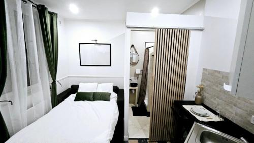 une petite chambre avec un lit et un lavabo dans l'établissement Studio Le Petit Valenciennois, à Valenciennes