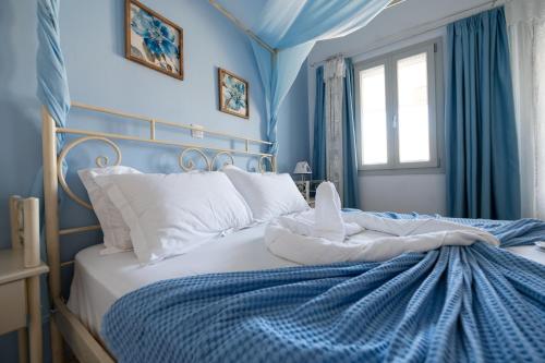 a bedroom with blue walls and a bed with white pillows at Giasemi Rooms in Livadi Astypalaias