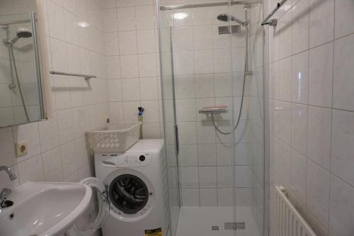 a bathroom with a shower and a washing machine at Kustverhuur, Oude manege, Nieuwvliet 14-16 in Nieuwvliet