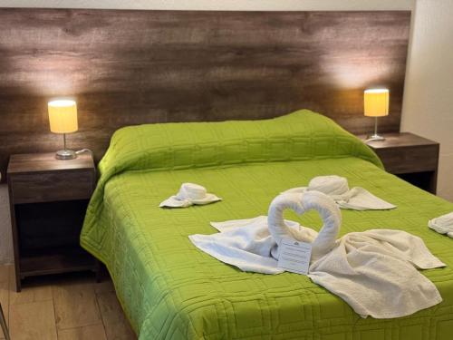 a green bed with towels and swans on it at Hotel Palace Piriápolis in Piriápolis