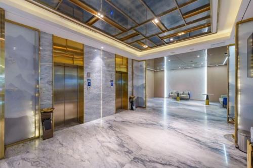un atrio di un edificio con ascensori e un divano di Bingo-威尔顿酒店-昆明火车站云纺商业城店 a Kunming