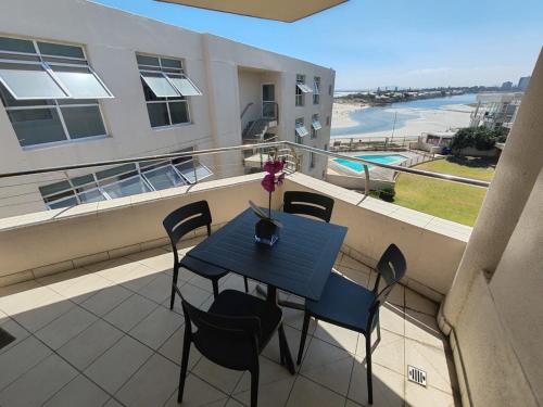 a blue table and chairs on a balcony with a view at Lagoon Beach Apartment 309 in Cape Town