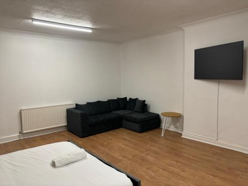 a living room with a black couch and a flat screen tv at Del Apartments in Warrington