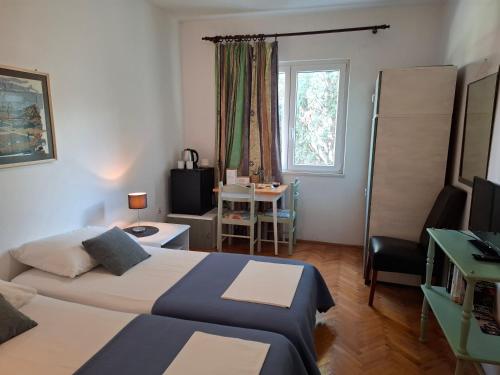a bedroom with two beds and a desk and a window at Apartments Mira in Cavtat