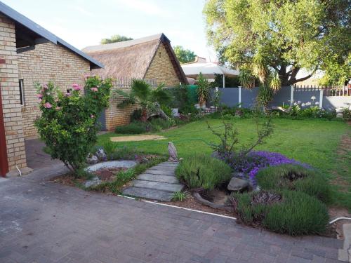 a garden with a brick house and a yard at Smirna Guesthouse in Vryburg