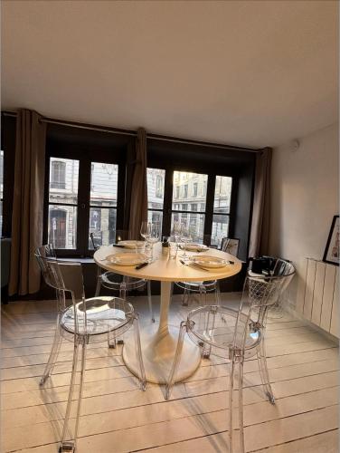 une table et des chaises dans une pièce avec des fenêtres dans l'établissement Le Cosy Terreaux, à Lyon