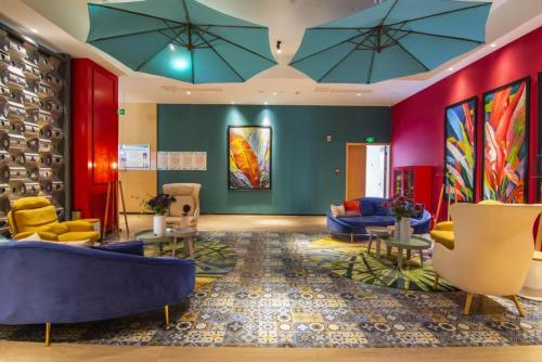 a lobby with blue couches and colorful paintings at Happy Inn-Zhengzhou Railway St ation Erqi Square Branch喜鹊愉家酒店锦荣国际轻纺城店 in Zhengzhou