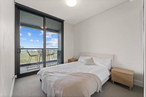 a white bedroom with a bed and a balcony at Luxury Retreat 2BR with Stunning Harbour Bridge & City Views in Sydney