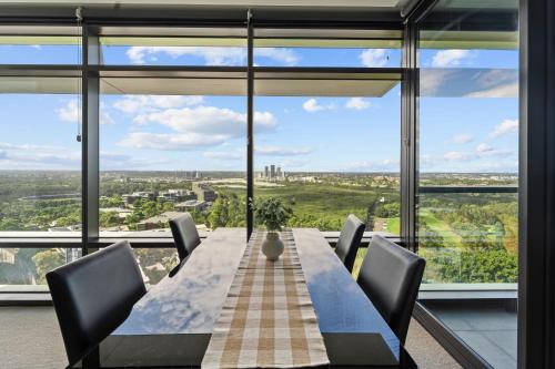 a dining room with a table and chairs and large windows at Luxury Retreat 2BR with Stunning Harbour Bridge & City Views in Sydney