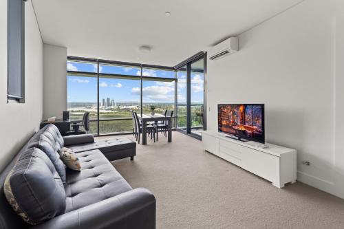 a living room with a couch and a flat screen tv at Luxury Retreat 2BR with Stunning Harbour Bridge & City Views in Sydney