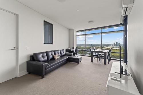 a living room with a black couch and a table at Luxury Retreat 2BR with Stunning Harbour Bridge & City Views in Sydney