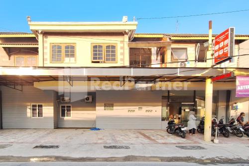 a building with motorcycles parked in front of it at Aster Triplets Guest House JCM Mitra RedDoorz in Yogyakarta