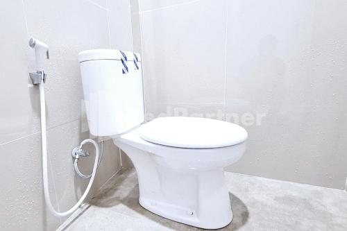 a white toilet in a bathroom with a shower at Aster Triplets Guest House JCM Mitra RedDoorz in Yogyakarta