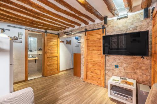 a living room with a flat screen tv on a stone wall at Apartamentos cuna del Genil in Güéjar-Sierra