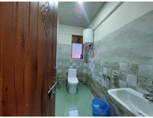 a bathroom with a toilet and a sink and a door at Gaurs home stay badrinath Highway, Pandukeshwar in Pāndukeshwar
