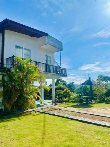 a large white house with a green yard at Bloom house homestay in Bandarawela