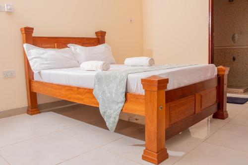 a wooden bed with white sheets and pillows at A Cozy 3 Bedroom Apartment With a Pool in Nyali in Mombasa