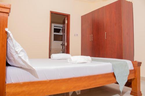 a bedroom with a bed and a wooden cabinet at A Cozy 3 Bedroom Apartment With a Pool in Nyali in Mombasa