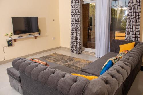 a grey couch in a living room with a tv at A Cozy 3 Bedroom Apartment With a Pool in Nyali in Mombasa