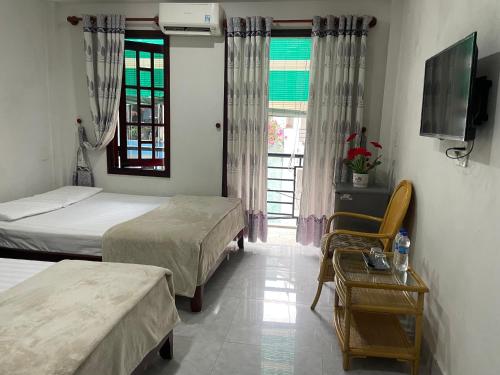 1 dormitorio con 2 camas, mesa y TV en Homestay 52, en Hue
