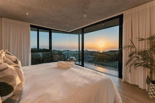 a bedroom with a bed and a balcony with the sunset at Theunieskraal Nkwazi Ridge Estate in Zinkwazi Beach