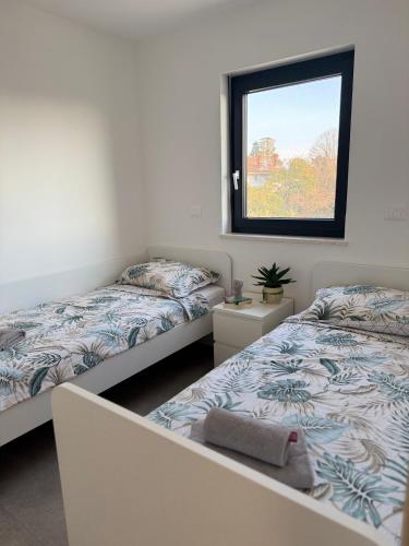 two beds in a room with a window at Apartments Frank in Zambratija