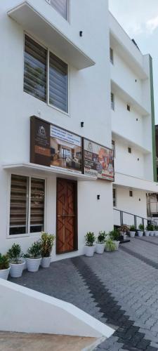 a white building with a brown door and some plants at Hotel Eden Palace in Trichūr