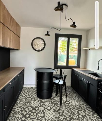 une cuisine avec des armoires noires, une table et des chaises dans l'établissement Entièrement rénové, à Saint-Laurent-de-la-Salanque