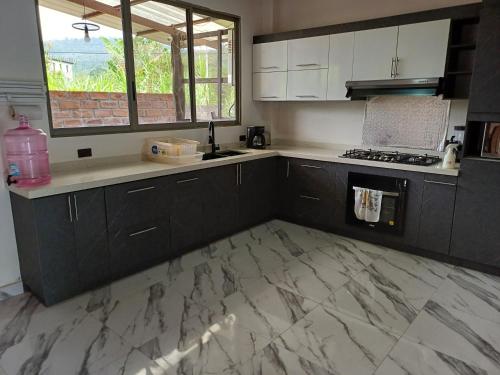 eine Küche mit schwarzen Schränken und Marmorböden in der Unterkunft Carachula Guesthouse in Macas