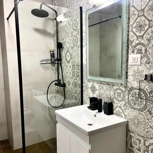 a bathroom with a shower and a sink and a mirror at V&P Apartments in Bitola
