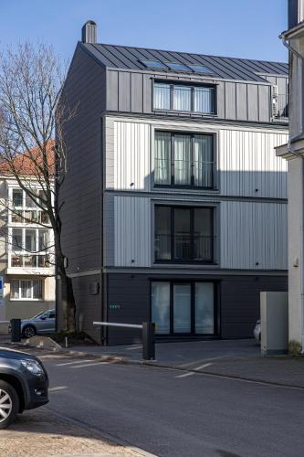 a black and white building with a car parked in front at Karoso rezidencija in Klaipėda