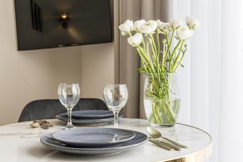 a table with plates and glasses and a vase of white flowers at Karoso rezidencija in Klaipėda