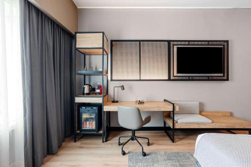 a room with a desk and a tv and a chair at NH Collection Monterrey San Pedro in Monterrey
