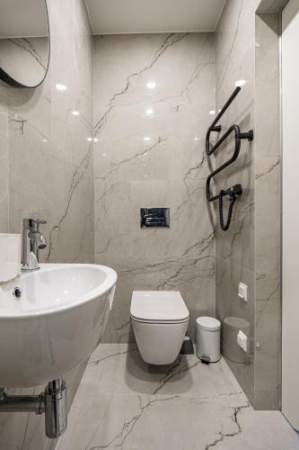 a bathroom with a white toilet and a sink at Karoso rezidencija in Klaipėda