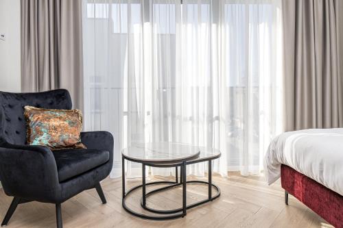 a bedroom with a bed and a chair and a table at Karoso rezidencija in Klaipėda