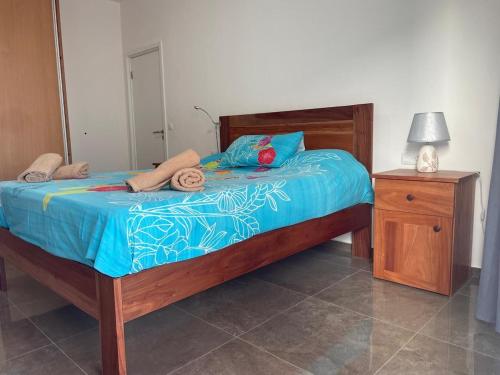 a bedroom with a bed with blue sheets and a night stand at Casa Tubarào in Vila do Maio