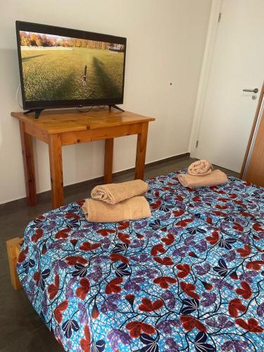 a bedroom with a television and a bed with towels at Casa Tubarào in Vila do Maio