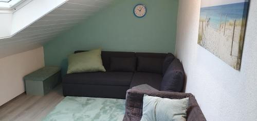 a living room with a black couch and a clock at Auszeit in Wald-Michelbach