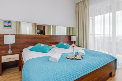 a bedroom with a large bed with blue and white sheets at Atrium Spa Practical Studio Near the Beach by Noclegi Renters in Sarbinowo