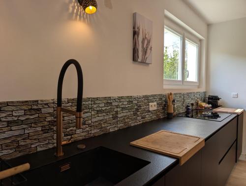 - une cuisine avec un plan de travail noir et un évier dans l'établissement La villa Brévinoise - Elégante maison pour 6 personnes, à Saint-Brévin-les-Pins