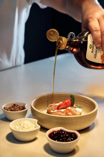 a person pouring sauce into a bowl of food at Hotel Palais Mailberger Hof in Vienna