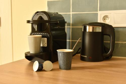 a coffee maker and two cups on a counter at For Me Formidable in LʼIsle-Jourdain