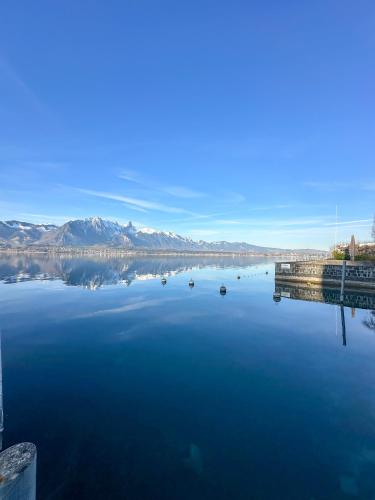 a large body of water with a dock and mountains at Room's at HAUS am SEE direkt am Thunersee gelegen mit SELF CHECK IN & digitaler Rezeption in Oberhofen am Thunersee