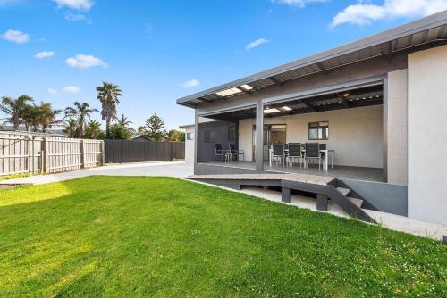 a house with a patio and a grass yard at Paradise on Peninsula in Safety Beach