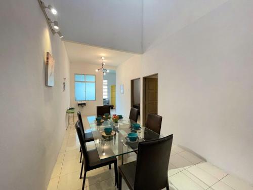 a dining room with a glass table and black chairs at Jovial Single Storey Cozy Haus 9Pax in Lunas