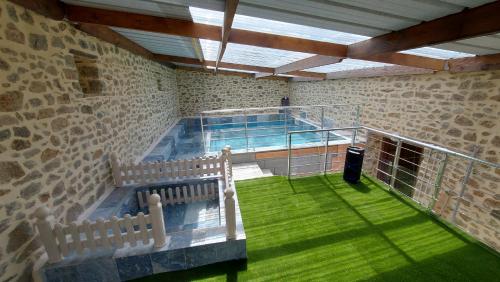 - une grande piscine dans un bâtiment avec de l'herbe verte dans l'établissement Gite LA ROCHERIE, à Hambers